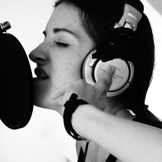 female vocalist singing into a studio microphone